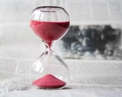Close-up of a glass hourglass with red sand running through, symbolizing the time remaining to finish the year strong financially