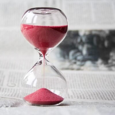 Close-up of a glass hourglass with red sand running through, symbolizing the time remaining to finish the year strong financially