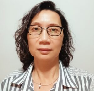 Headshot of Elsie Lim, a financial literacy trainer at Empower2Free Singapore, wearing glasses and a striped shirt.