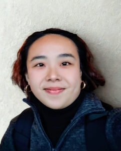 Headshot of Ivy Seow, a financial literacy facilitator at Empower2Free Singapore, smiling and wearing gold hoop earrings